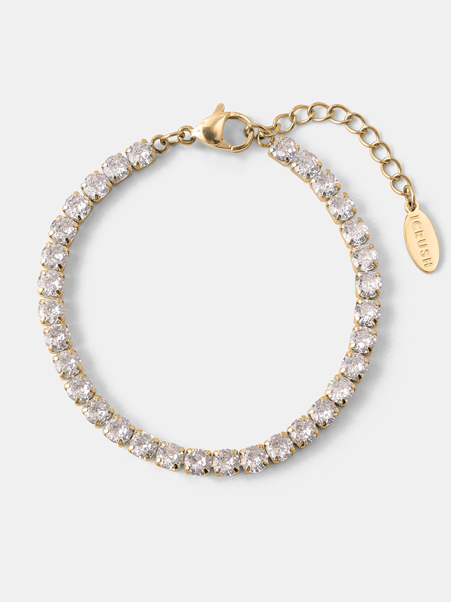 Goldenes Gliederarmband mit funkelnden weißen Steinen, Lobster-Verschluss, Kettchenverlängerung und Anhänger, flach liegend.