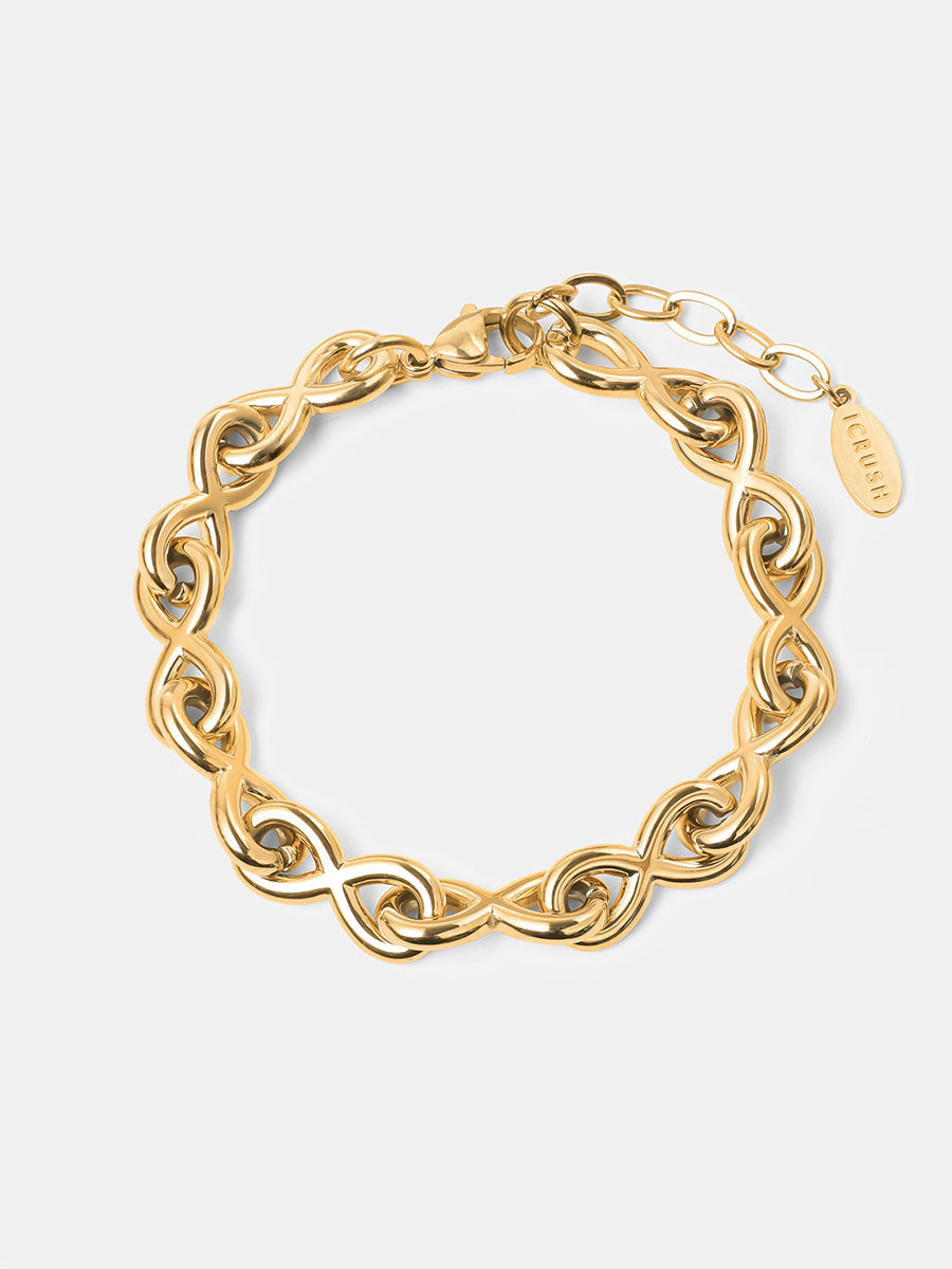 Flach liegendes goldfarbenes Gliederarmband mit Unendlichkeitsmotiv, Verlängerungskette und kleinem Markenanhänger.