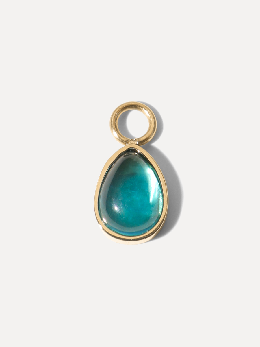 Goldener tropfenförmiger Charm mit blaugrünem Cabochon und kleiner Öse, Studioaufnahme.