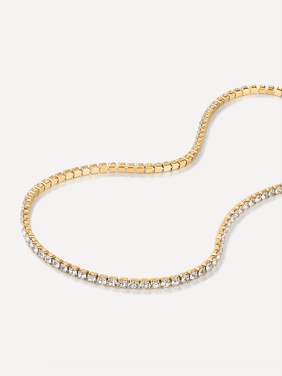 Goldfarbene Halskette, obere Hälfte eckige Boxkette, untere Hälfte funkelnde Steinkette, heller Hintergrund.