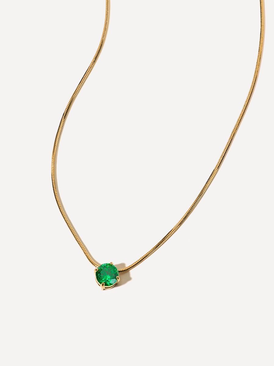 Goldene Halskette mit rundem grünem Anhänger, feine Schlangenkette, weißer Hintergrund.