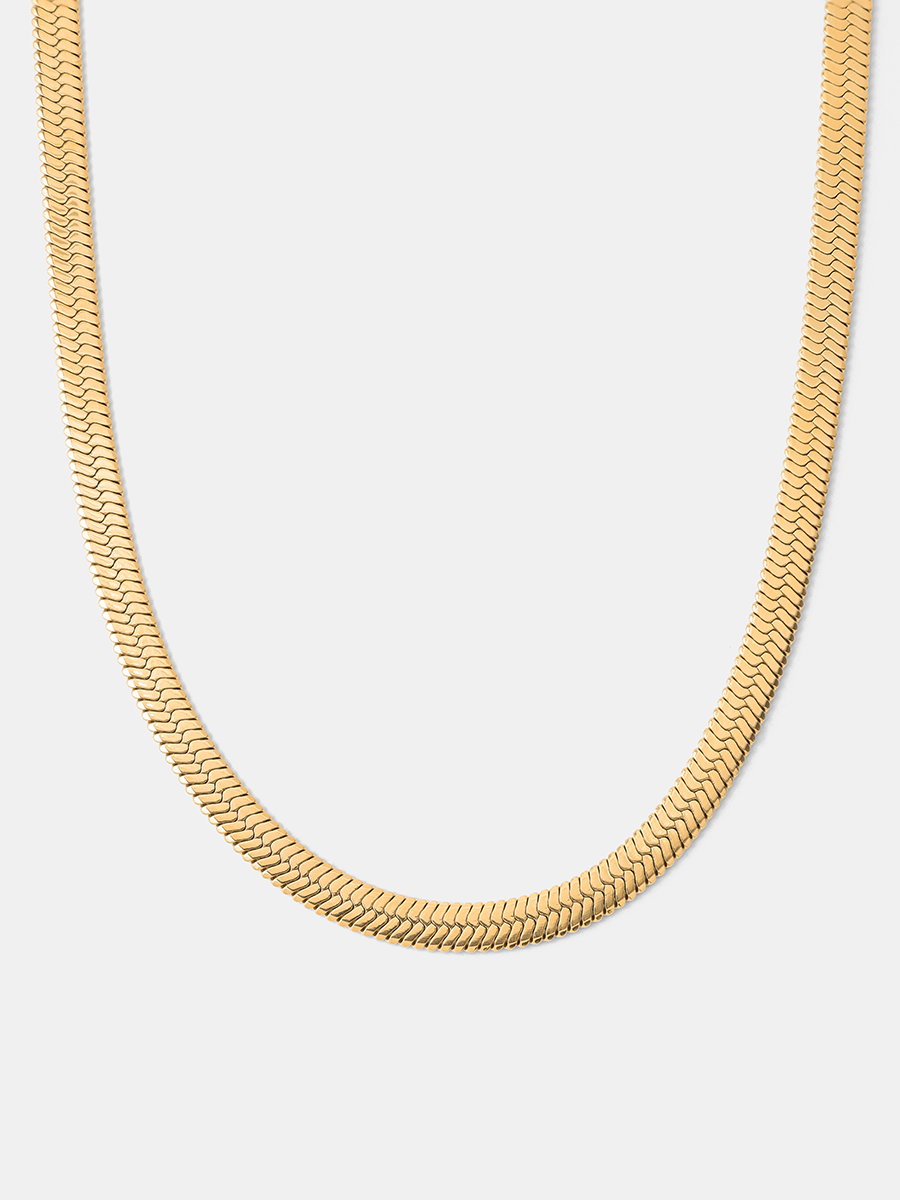 Goldfarbene Fischgrätenkette liegt als U auf hellem Grau, feine Glieder, kein Anhänger.