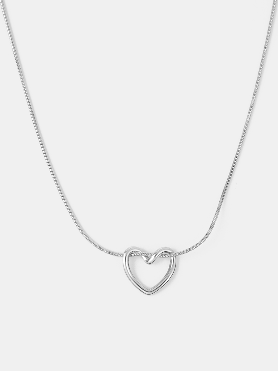 Silbernes Collier mit offenem Herzanhänger, durchgefädelt, schimmernde Oberfläche, heller Hintergrund.
