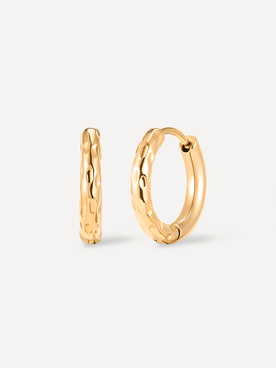 Goldene Creolen in kleiner Kreisform, eine seitlich und eine frontal, mit welliger Metalloberfläche.