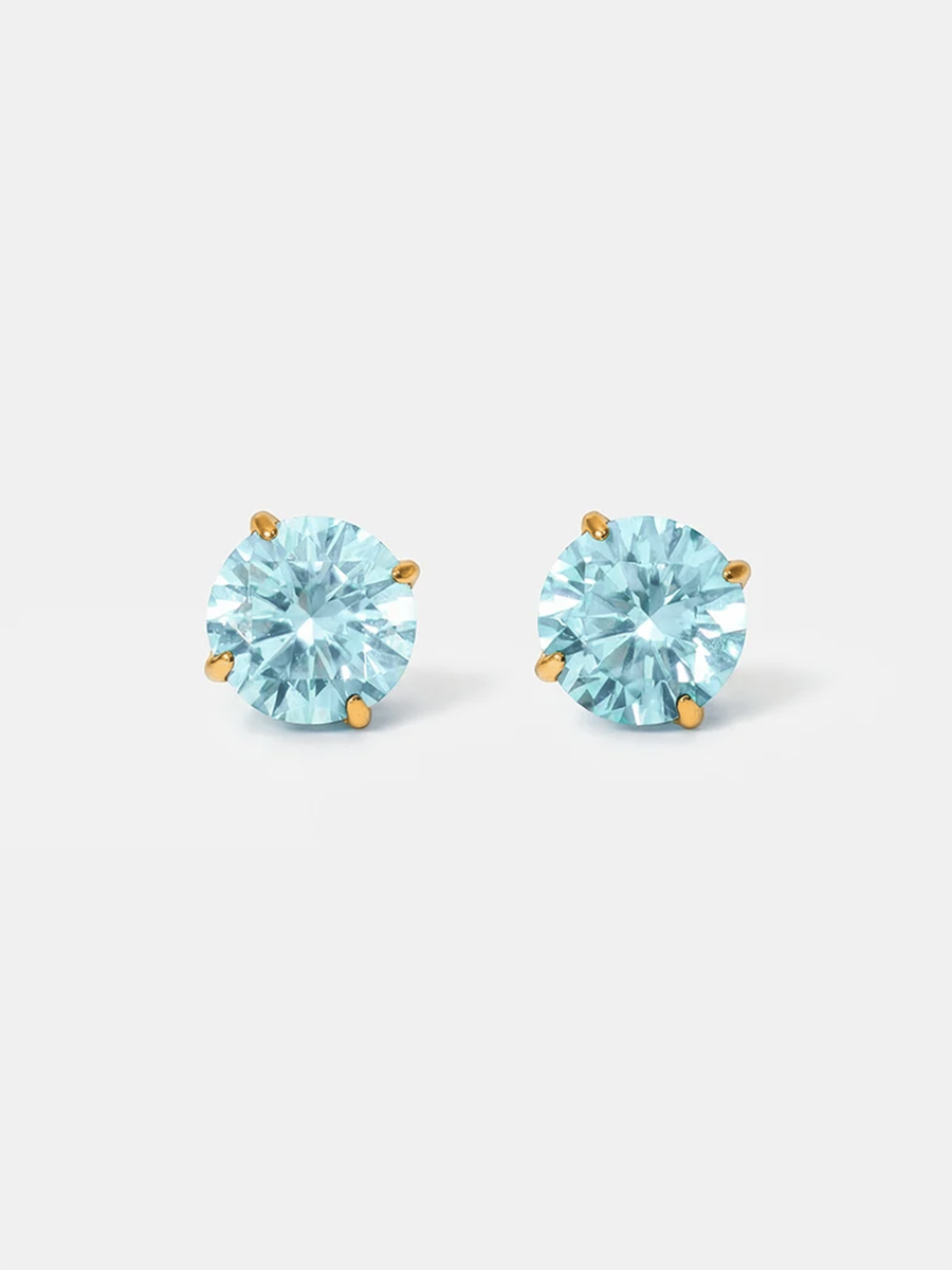 Zwei Ohrstecker mit runden hellblauen Kristallen und goldfarbenen Krappen auf schlichtem Weiß.