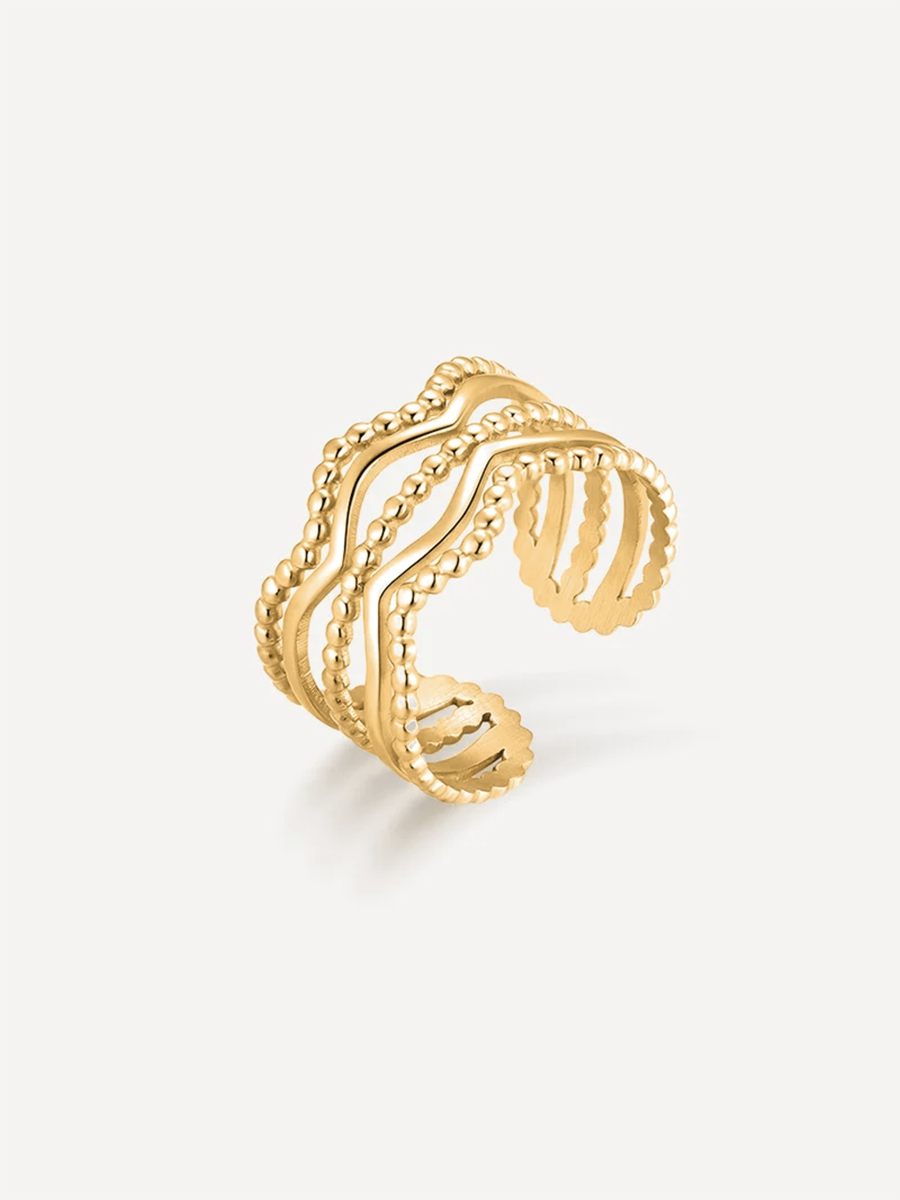 Goldener Ripple Ring als welliger, offener Fingerring mit mehrreihiger Perlenkante vor hellem Studiohintergrund.