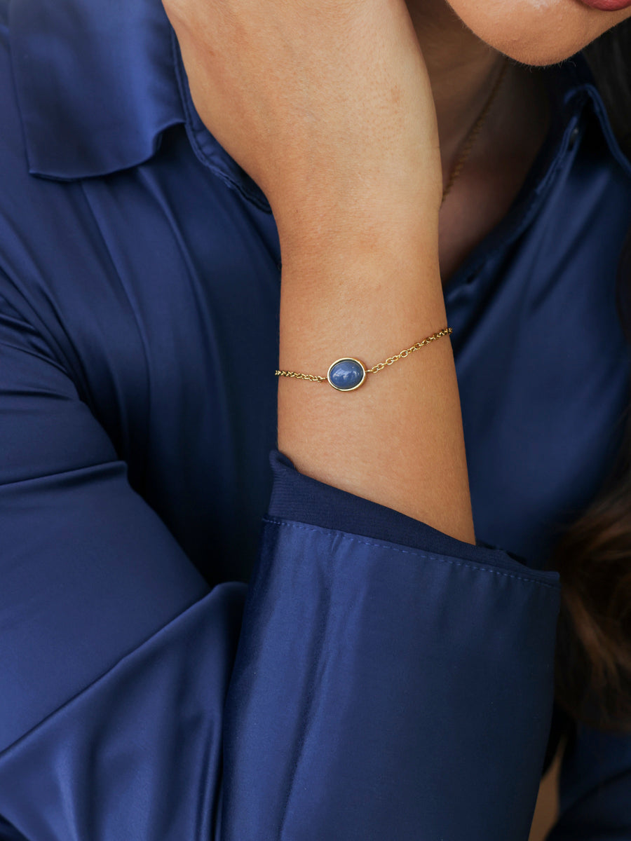 Blauer Aventurin als Anhänger an einer Goldkette über einer dunkelblauen Bluse