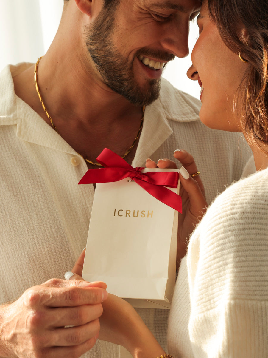 Weihnachtsgeschenk nach Person: Paar mit ICRUSH-Geschenktuete und roter Schleife.