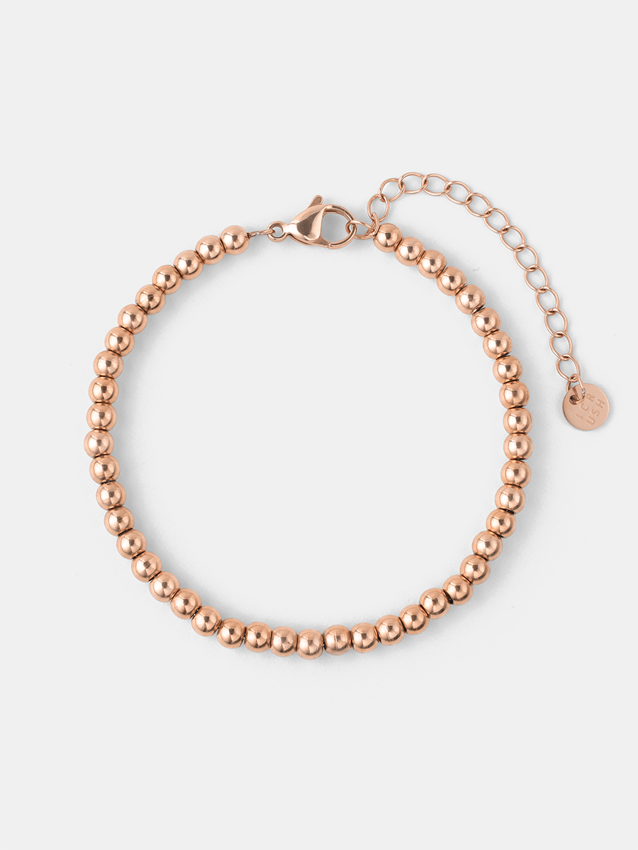Roségoldfarbenes Kugelketten-Armband mit Karabiner, Verlängerungskette und kleinem rundem Anhänger auf Weiß.
