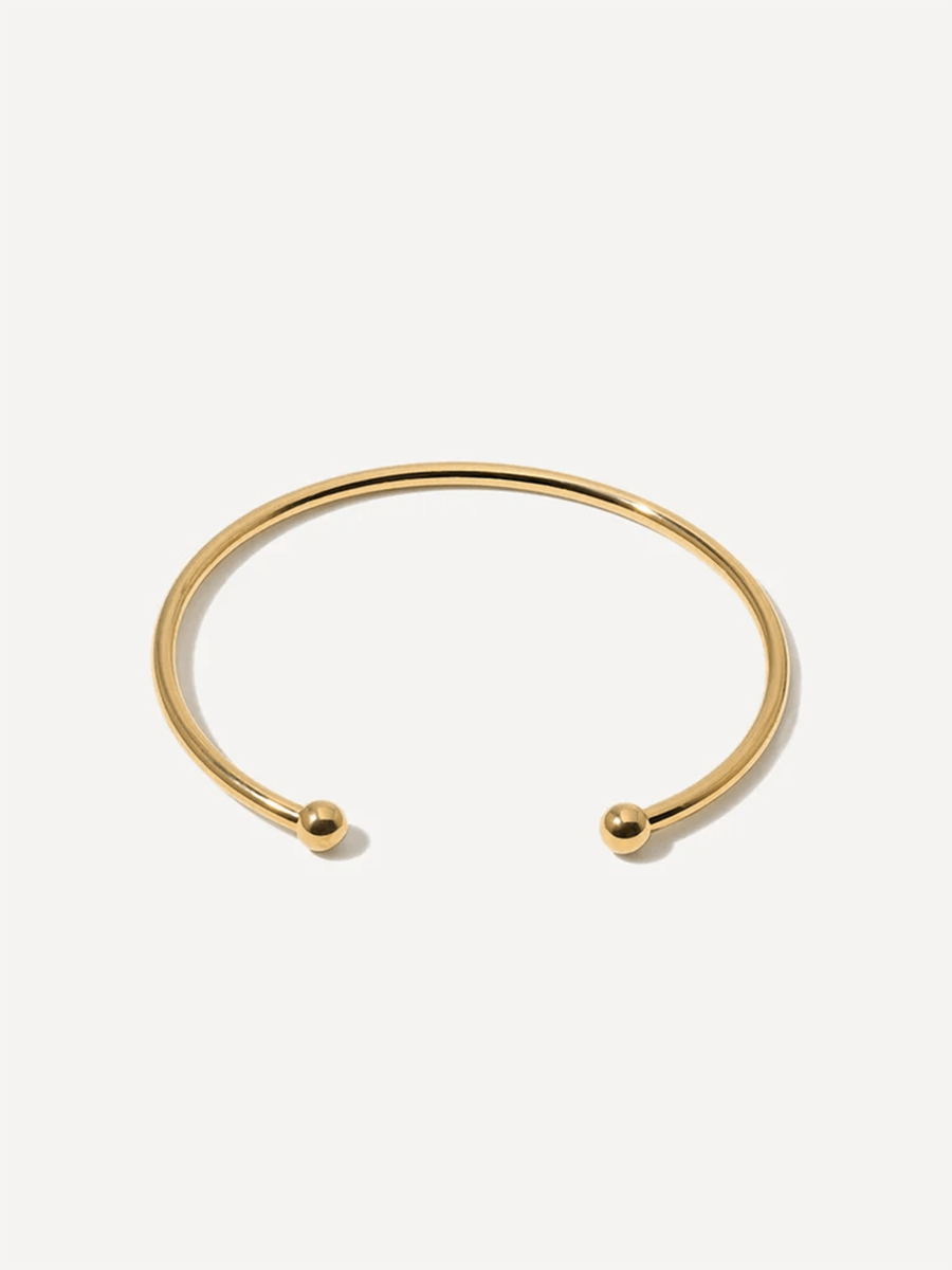 Produktaufnahme: goldener Armcuff mit runden Enden, offene Form, vor neutraler Fläche.