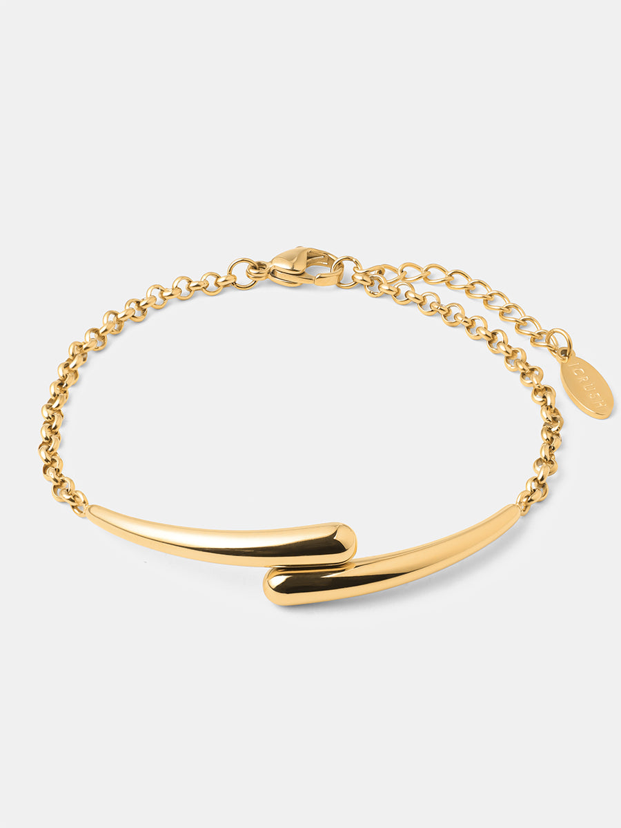 Goldenes Armband liegend auf grauem Hintergrund, überlappender Bügel, Kettchen und Verschluss.