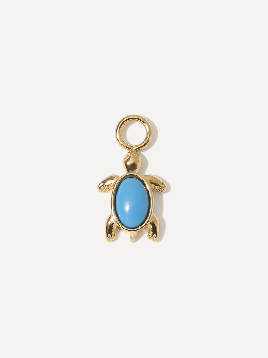 Goldfarbener Meeresschildkröten-Charm mit türkisblauem Cabochon und runder Aufhängung auf neutralem hellem Studiohintergrund.