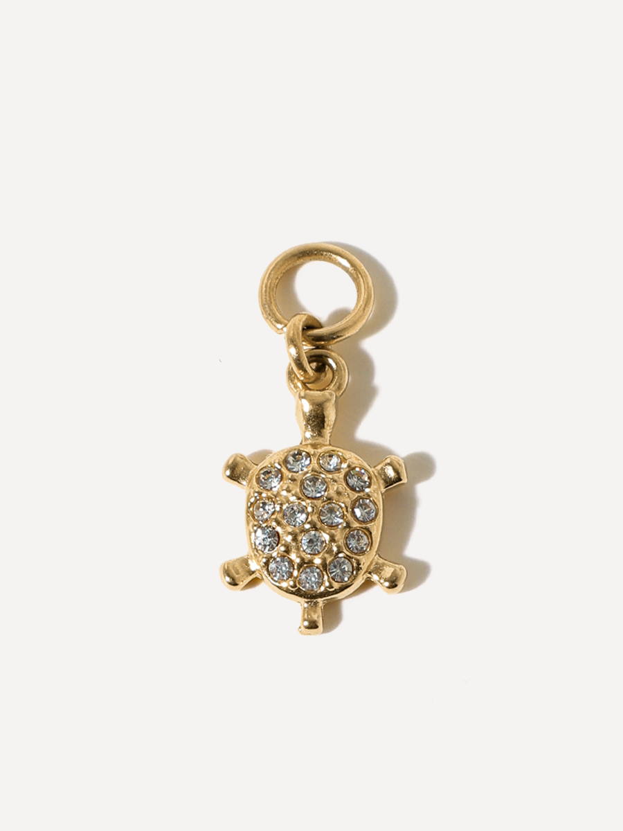 Goldener Turtle-Anhänger mit Befestigungsring, Steinen und Öse vor weißem Hintergrund.
