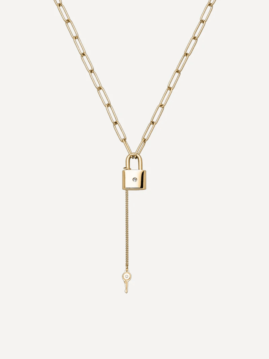 Goldfarbene Gliederkette mit Schloss und kleinem Schlüssel auf schlichtem, hellem Untergrund.
