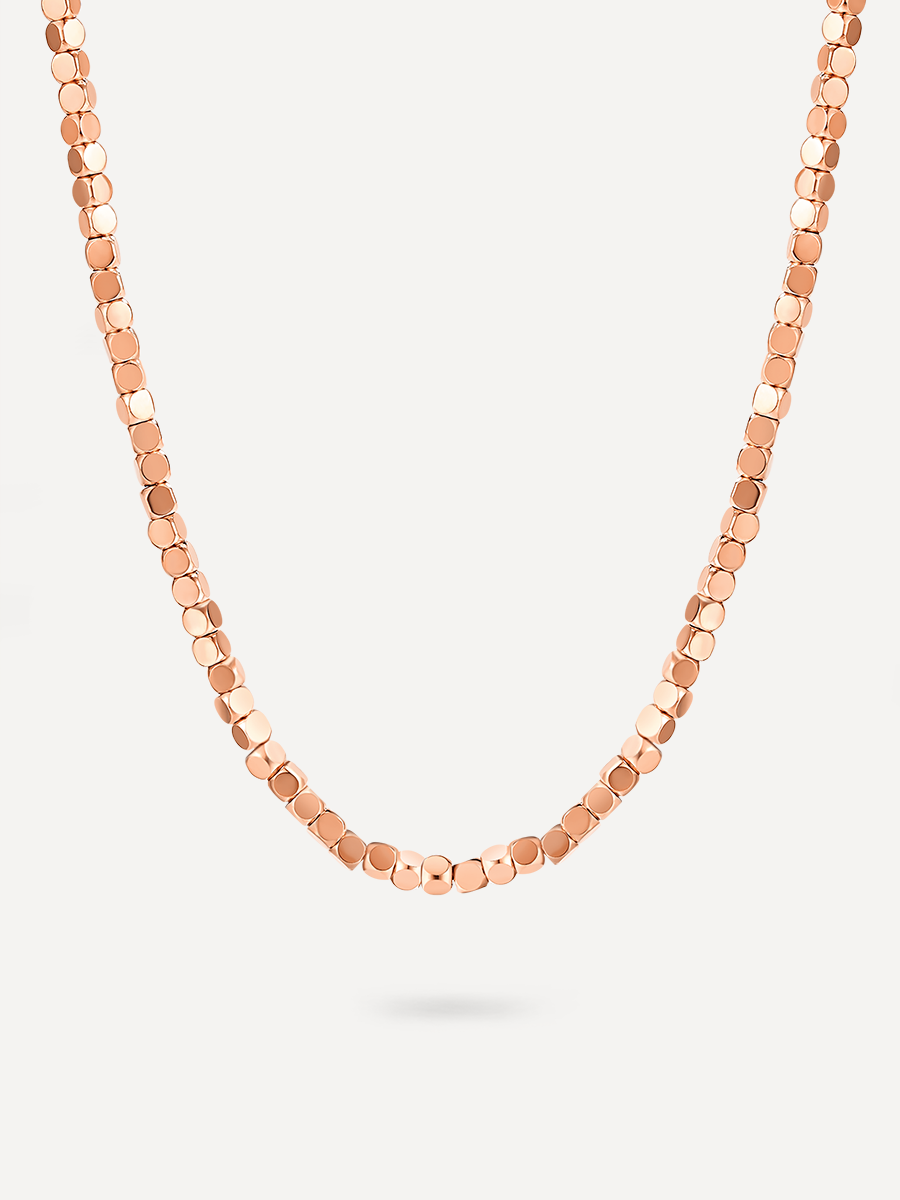 Roséfarbene Halskette mit flachen, runden Plättchen vor neutralem Hintergrund, Verschluss nicht erkennbar.