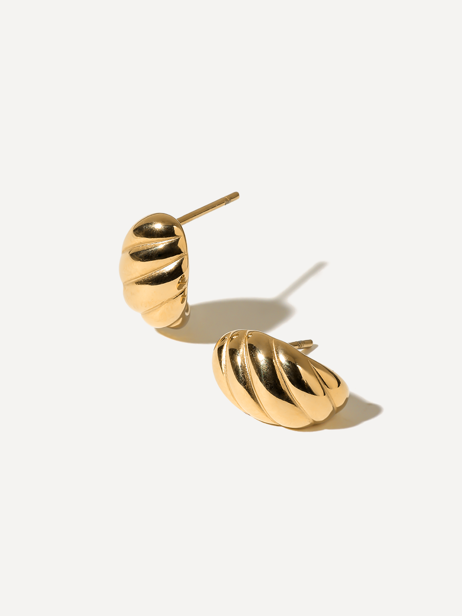Goldglänzende Ohrstecker mit Rippenprofil, aufrecht und flach liegend, vor einfarbigem Hintergrund.