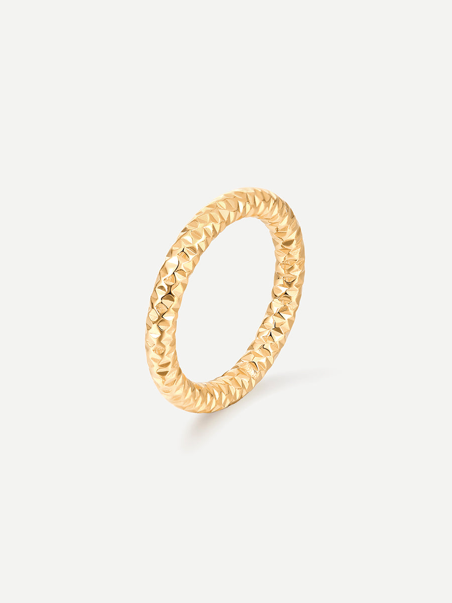Goldener Ring mit gedrehter Struktur steht schräg vor weißem Studiohintergrund.