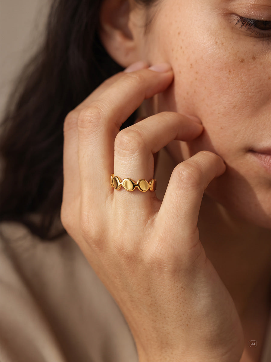 Seitliche Gesichtsaufnahme zeigt goldfarbenen Plättchenring am Finger, sommersprossige Haut und dunkles Haar.