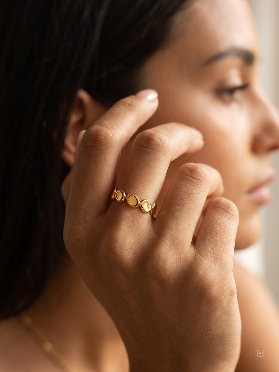 Frau im Profil trägt goldenen offenen Plättchenring, dünne Halskette und unscharfer heller Hintergrund.