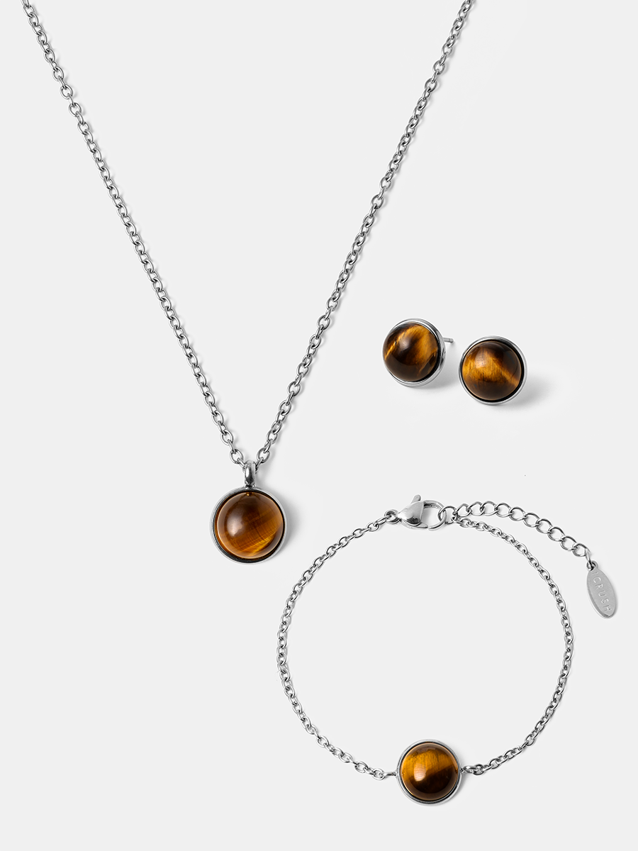 Silberfarbenes Set flach auf hellem Untergrund: Kette mit Anhänger, Ohrstecker und Armkettchen, kugeliger Tigerauge.